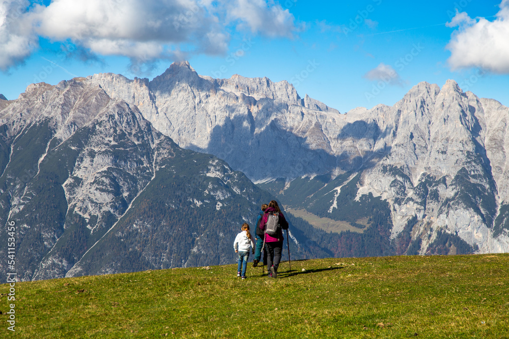 Wandern mit Kindern in Seefeld, Tirol: Familie wandert über eine Almwiese, im Hintergrund das Wettersteingebirge