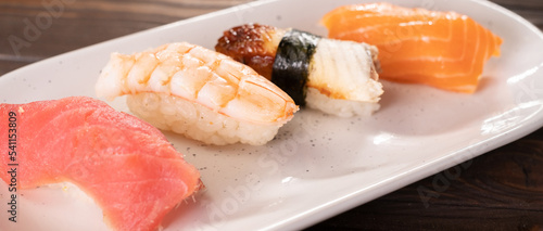 Nigiri sushi with salmon, eel, tuna and prawn, served on white plate. Delicious traditional Japanese food, tasty seafood, restaurant menu, food background