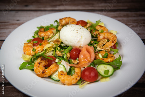 Recipe for rocket salad  endive  tomato  cucumber  soft-boiled egg  fried shrimp with paprika  smoked salmon and nuts. High quality photo