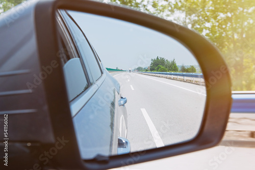 Landscape in the side view mirror of a car on the road.
