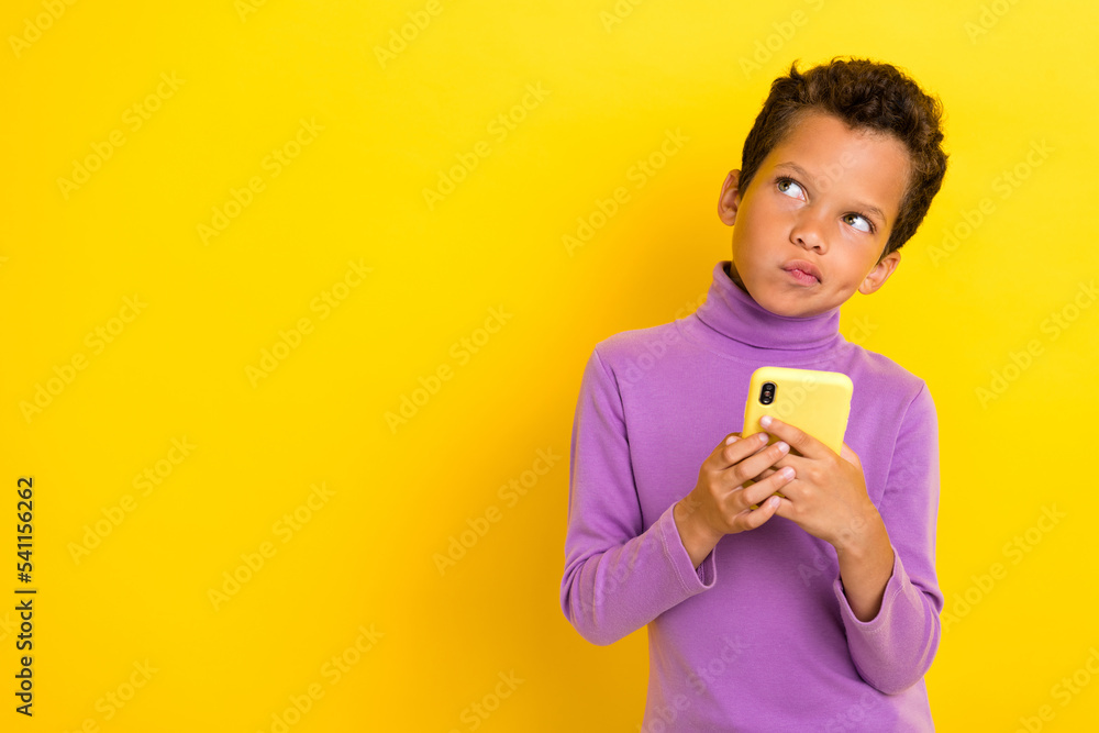 Photo portrait of adorable little boy hold telephone look skeptical copyspace wear trendy violet outfit isolated on yellow color background Photo portrait of adorable little boy hold telephone look skeptical copyspace wear trendy violet outfit isolated on yellow color background