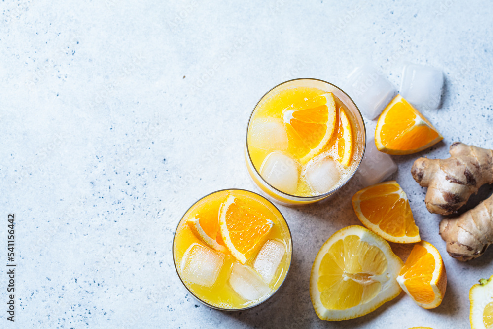Orange lemon juice with ginger and spices in glass, gray background. Immunity boosting drink, health concept, recipe for colds. Orange lemon juice with ginger and spices in glass, gray background. Immunity boosting drink, health concept, recipe for colds.