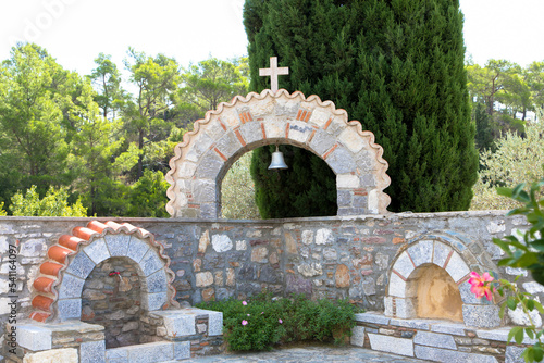 Sandstone arch with bell and religious cross in front of a wild and romantic landscape. Seen at Moni Thari Monastery in Laerma. Rhodes Island, Dodecanese,
South Aegean, Greece photo