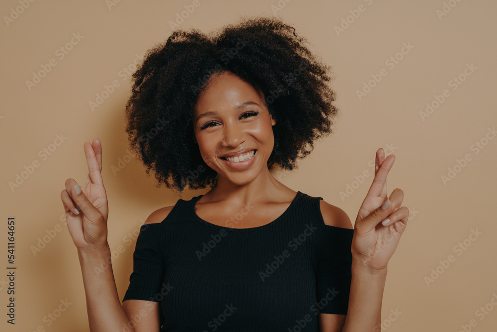 Portrait of happy young african woman standing isolated over dark beige background with copy space Portrait of happy young african woman standing isolated over dark beige background with copy space