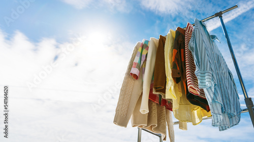  Low angle view at colourful clothes hanging on rail against blue sky. photo