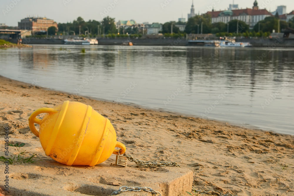 yellow plastic buoy lies on the sand on the bank of the river in summer yellow plastic buoy lies on the sand on the bank of the river in summer