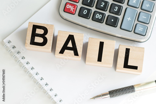 word BAIL on wooden cubes on blue background. the inscription on the cubes is reflected from the surface. business concept