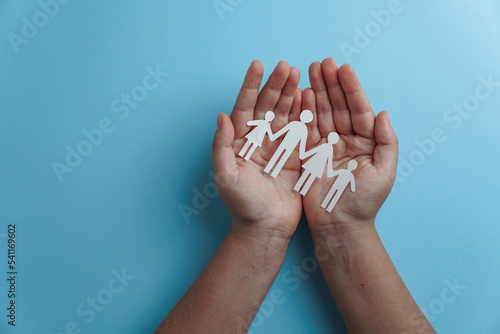 hands holding paper family cutout, life health insurance, social distancing concept, covid19, on the blue color background, family protection