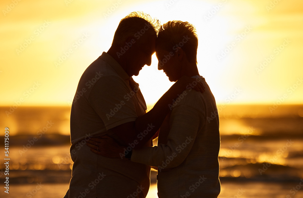 Couple, elderly and silhouette at beach with hug in sunset, evening or dusk by water, waves or horizon together. Senior, man and woman by ocean, sea or sunshine for care, affection or love in romance