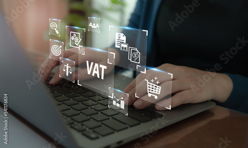 VAT concept. Value Added Tax. Officer working on computer with VAT text and iconon smart background.