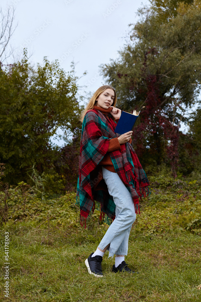 a beautiful woman walks in the autumn park with a book in her hands a beautiful woman walks in the autumn park with a book in her hands