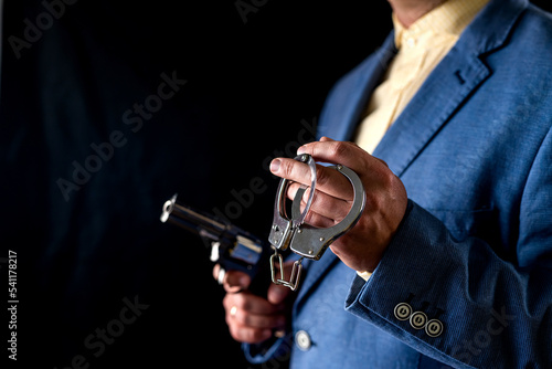 Cropped photo of brutal angry thug in tuxedo with revolver in hand isolated on black background