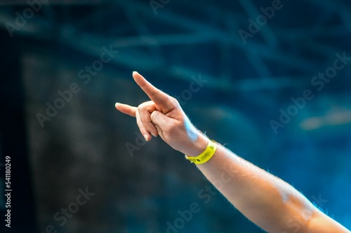 Closeup shot of an arm with a wristband doing a rock sign at a festival photo