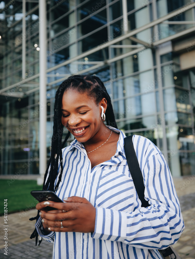 Fototapeta premium Black business woman using a smartphone while commuting in the city
