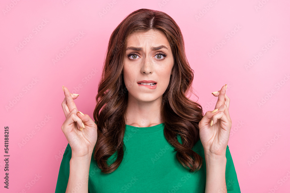 Portrait of pretty gorgeous girl with curly hairstyle wear green t-shirt fingers crossed biting lip isolated on pink color background Portrait of pretty gorgeous girl with curly hairstyle wear green t-shirt fingers crossed biting lip isolated on pink color background