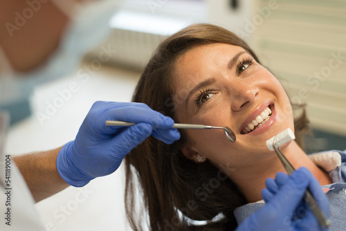 Dentist repairing and checking teeth of a young woman  at the dental clinic