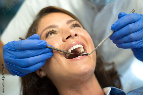 Dentist repairing and checking teeth of a young woman at the dental clinic