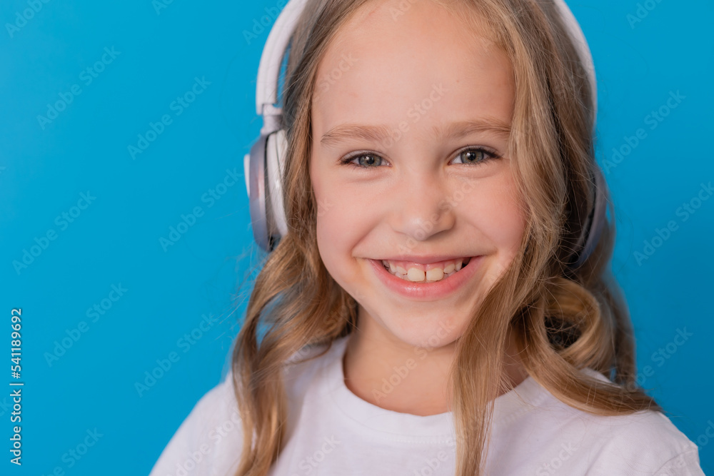 blonde girl in jeans and a white T-shirt listens to music with headphones and dances blonde girl in jeans and a white T-shirt listens to music with headphones and dances