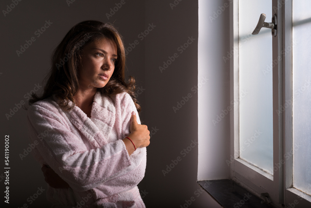 Young woman in bathrobe suffering from cancer standing beside hospital window Young woman in bathrobe suffering from cancer standing beside hospital window