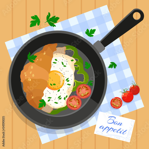 Frying pan with croissant and fried eggs, slices of tomatoes, peppers and parsley in a checkered pan and bon appetit card