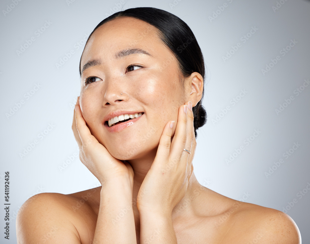Asian woman, face glow and skincare routine with hands touching cheeks on grey studio background. Smile, happy or beauty model in healthy wellness, relax self love dermatology or hydrated skin facial