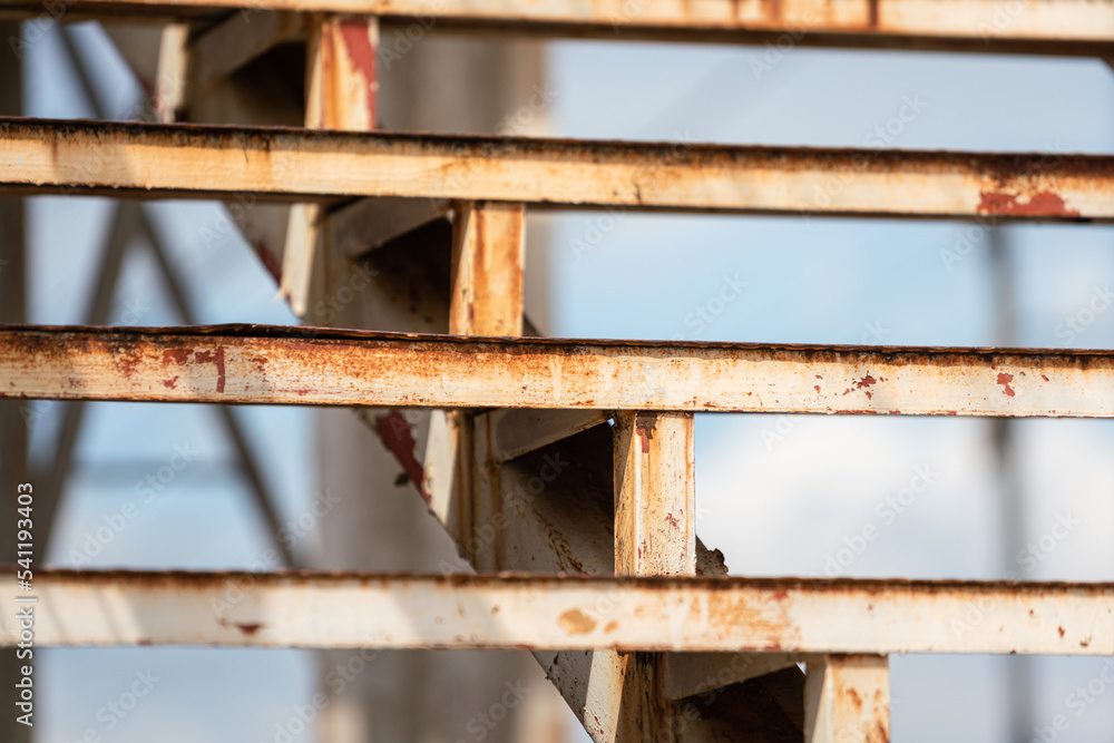 Close-up at step and banister part of the rustic stairway platform at the factory placed. Industrial equipment object photo, selective focus. Close-up at step and banister part of the rustic stairway platform at the factory placed. Industrial equipment object photo, selective focus.