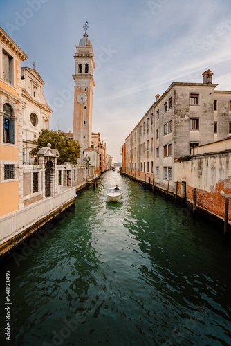 Motor boat sailing past the church of San Giorgio dei Greci with its typical leaning bell tower