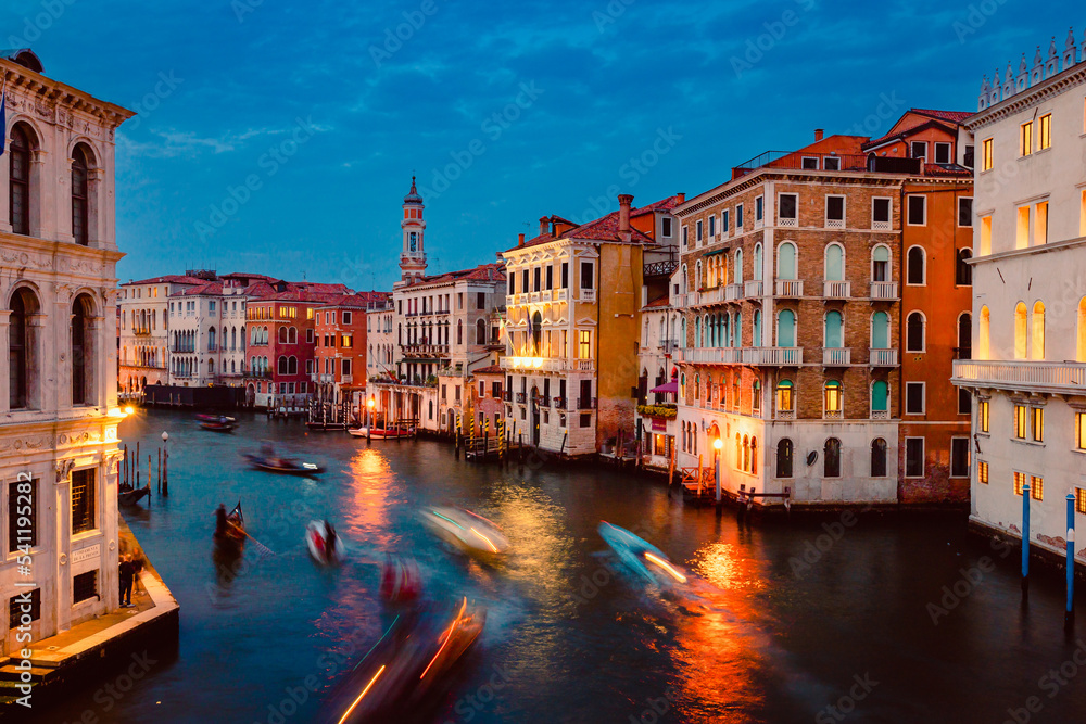 View of Venice's Grand Canal at sunset with illuminated historic buildings and light trails of tourist boats