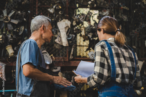 mechanic technician team wearing uniform reading or writing clipboard document and standing in auto repair shop garage, with car vehicle background, job of auto garage service concept