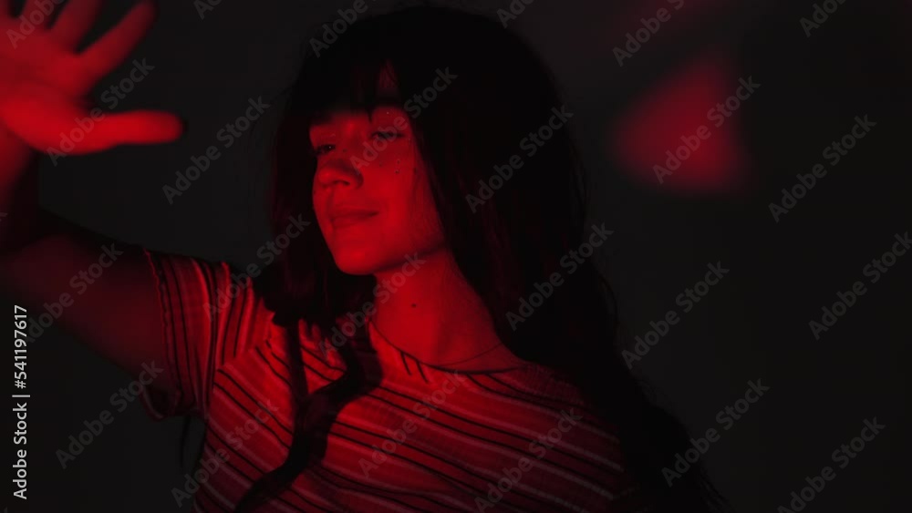 Young Woman Covered Her Face With Her Hand While Looking At The Red Light In Dark Room. Close up Young Woman Covered Her Face With Her Hand While Looking At The Red Light In Dark Room. Close up