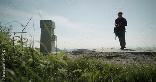 A young man reaching the peak of mountain Mrzlica in Slovenia, approaching a small station where he gets a stamp to record his climb. photo