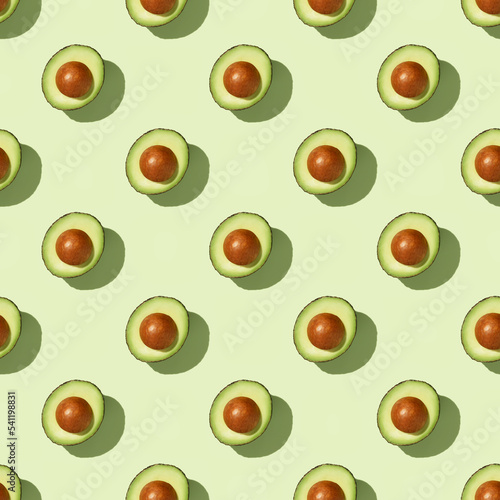 Avocado on green background pattern top view flat lay