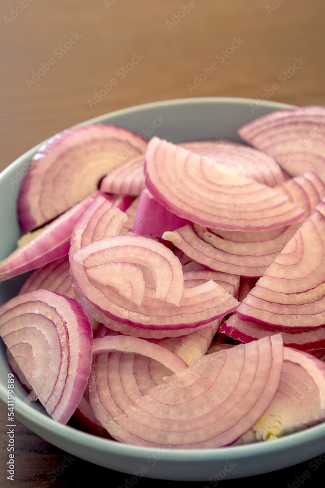 cut raw  red onion in blue bowl on the kitchen table
