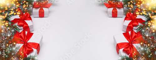  Spruce, fir branches, red berries, gift box on red background. Frame border. Christmas New Year composition background. Christmas lights. Space for text.