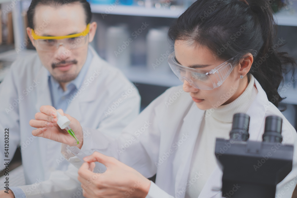Asain Female scientist is focusing and looking while dropping green substance in laboratory eco or natural cosmetic, medicine, organic skin care, biochemistry and studying concept. Asain Female scientist is focusing and looking while dropping green substance in laboratory eco or natural cosmetic, medicine, organic skin care, biochemistry and studying concept.