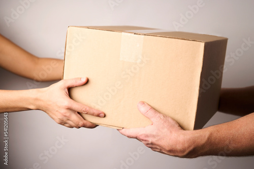 Fotótapéta Delivery man giving cardboard box to female hand