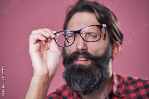 Foto Checking his glasses, shortsighted bearded man examining his spectacles, blurred