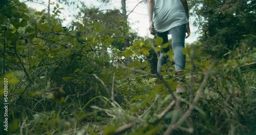 Traveler female walk through plants in forest on exploration trip adventure photo