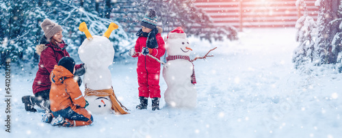 Obraz na płótnie Family bilding a cute snowman in the snowy park.