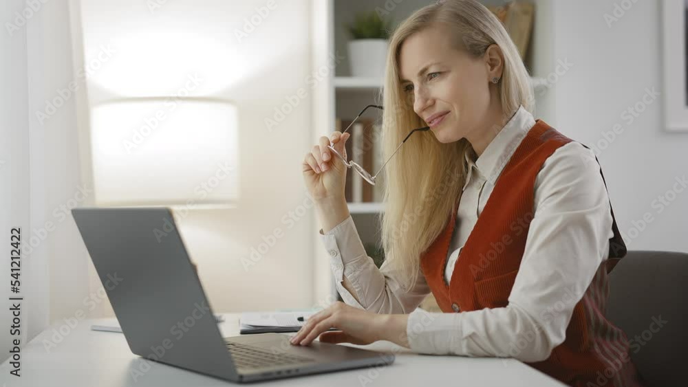 Smiling female freelancer workig from home, sitting at desk and checking results on laptop. Successful day Smiling female freelancer workig from home, sitting at desk and checking results on laptop. Successful day
