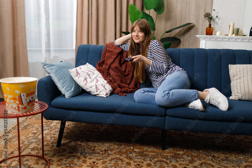 Obraz premium Woman switching tv channels while sitting on the sofa at home