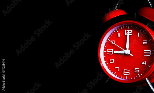 remote image of The red alarm clock is set to 9:00 a.m. on a dark background