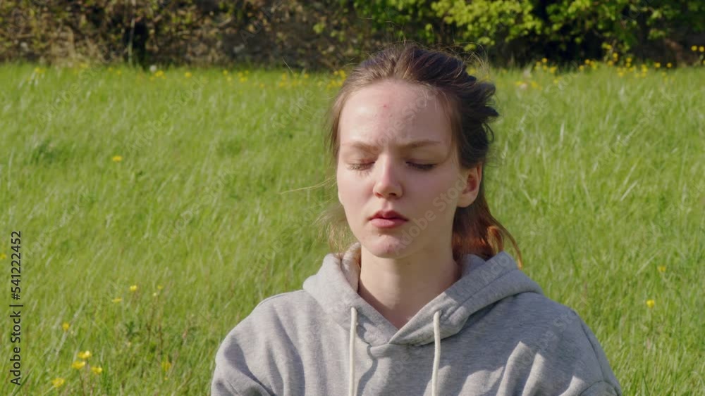 Female teenager keeping eyes closed and meditating at the cozy field Female teenager keeping eyes closed and meditating at the cozy field
