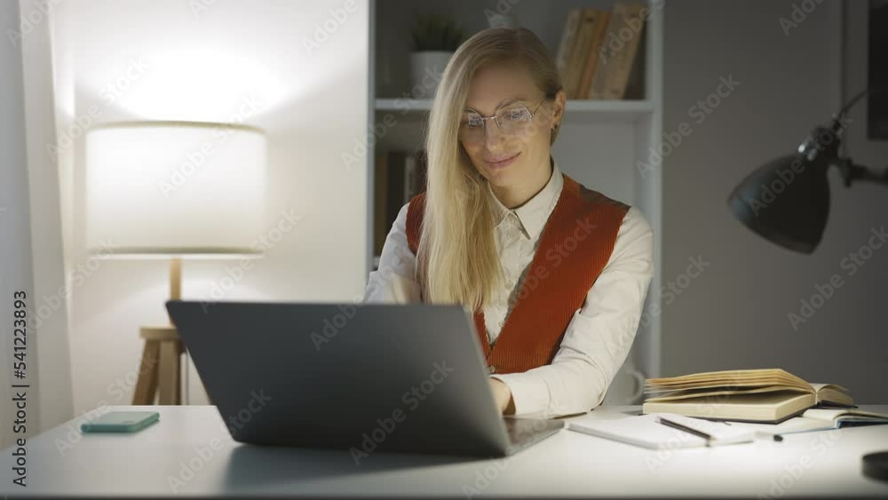 Nice beautiful lady with blonde hair working on laptop, texting in online messeger with friends and smiling, leisure evening time Nice beautiful lady with blonde hair working on laptop, texting in online messeger with friends and smiling, leisure evening time