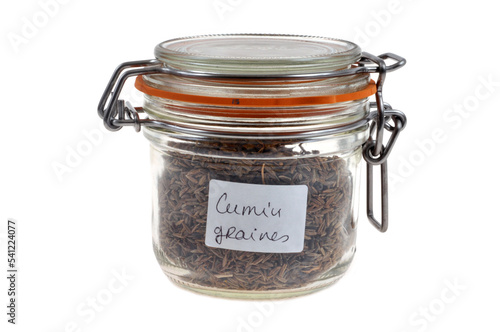 Bocal de graines de cumin en gros plan sur fond blanc