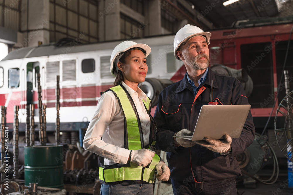 Copy space two engineer man and woman use laptop computer checking spares at factory spares train Copy space two engineer man and woman use laptop computer checking spares at factory spares train