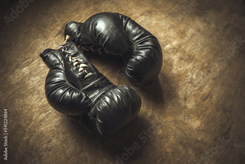 Vintage boxing gloves made of leather on a wooden table. The history of the boxer. An old boxing match. © Svetliy