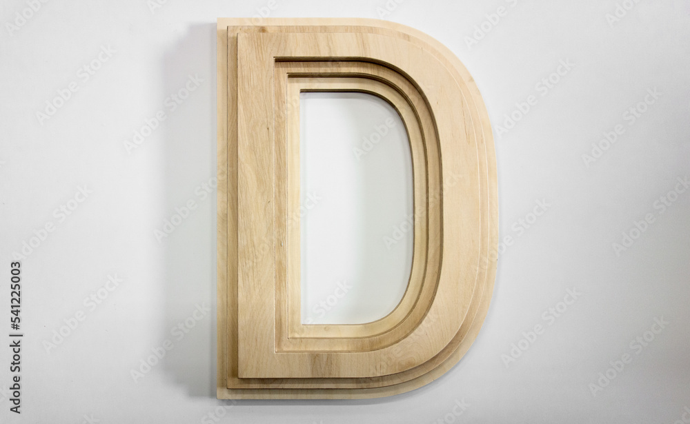Wooden letter D on a white background. Glued letter made of plywood. Cutting the logo out of wood. Wooden letter D on a white background. Glued letter made of plywood. Cutting the logo out of wood.