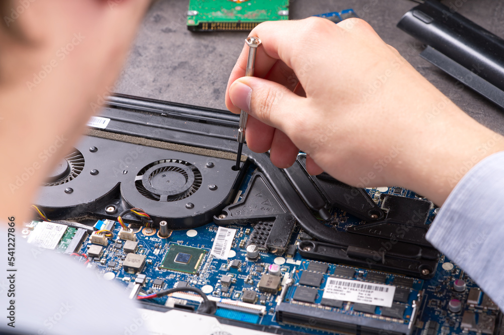 Hands fixing motherboard of pc or laptop notebook close up in service. Laptop repair service. PC hardware upgrade and maintenance. Engineer fixing broken notebook. Hands fixing motherboard of pc or laptop notebook close up in service. Laptop repair service. PC hardware upgrade and maintenance. Engineer fixing broken notebook.
