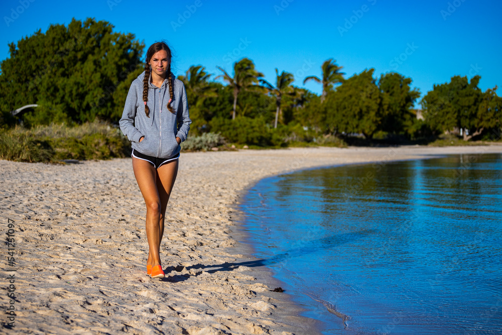 sweet girl in pigtails walks on coral bay beach at sunrise; warm morning on famous paradise beach in western australia, at ningaloo reef
